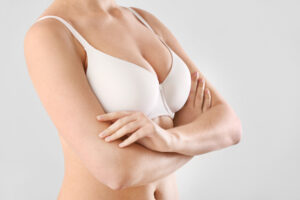 A cropped shot of a woman in a white bra with her arms crossed over her chest