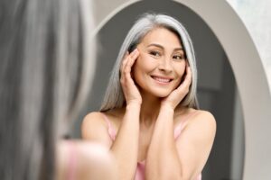 A woman looking in the mirror considering anti-aging treatments like microneedling