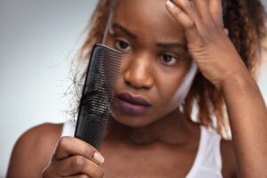 A woman experiencing hair loss looking at a comb and considering PRP